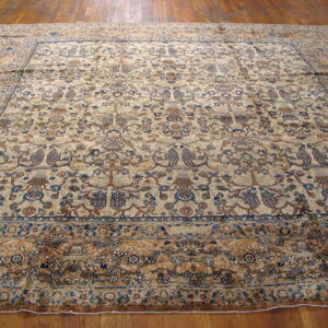 Ornate area rug in beige, navy, and rust colors with a dense pattern covering wood flooring.