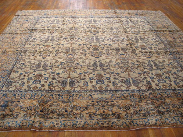 Ornate area rug in beige, navy, and rust colors with a dense pattern covering wood flooring.