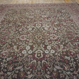 Large low-pile rug with intricate floral pattern in dark brown, burgundy, and cream on wooden floors.