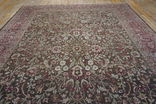 Large low-pile rug with intricate floral pattern in dark brown, burgundy, and cream on wooden floors.