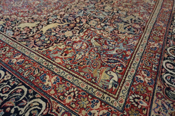 Intricate low-pile rug corner featuring red, navy, and cream colors with detailed bird and animal patterns.