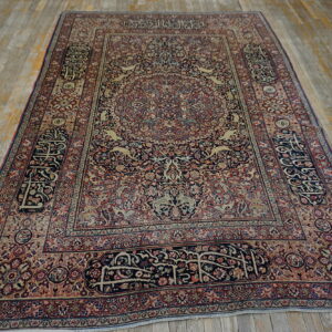 Ornate navy, red, and tan medallion rug with detailed animal motifs and calligraphy borders on distressed wood floors.
