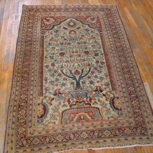 Low-pile beige, blue, and red traditional rug displaying a Tree of Life design on hardwood floors.