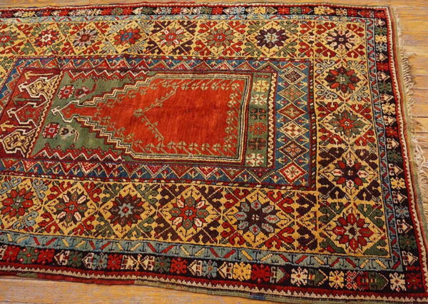 Geometric low-pile rug in red, yellow, green, and blue, featuring a central medallion, resting on wood floor.
