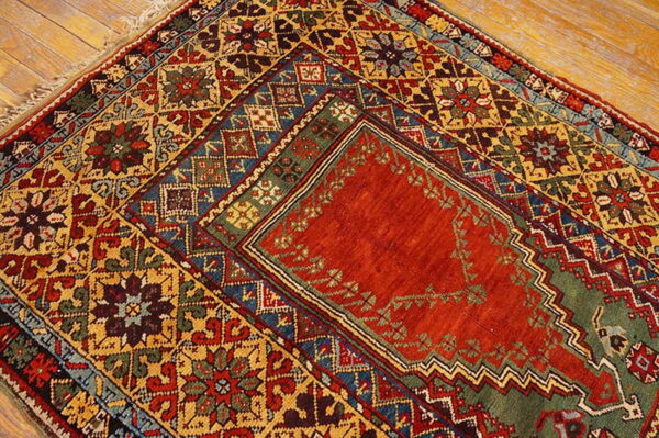 Highly detailed rug with a dense geometric pattern in red, gold, blue, and green on a wood floor.