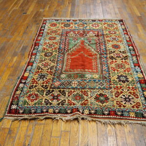 Ornate, multi-color rug with a central red arched design rests on weathered wood floors.