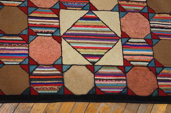 Hooked rug with multicolored striped diamonds and solid brown/rose octagons on light wood flooring.