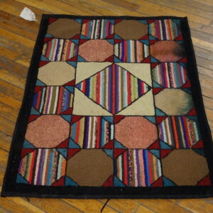 Geometric hooked rug featuring multicolored stripes and solid shapes, bordered in black on wood floors.