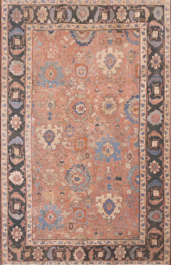 Low-pile floral rug with a distressed dusty rose field and detailed charcoal and blue borders.