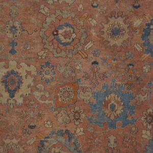 Intricate, low-pile rug pattern featuring faded traditional floral motifs in blue, rose, and beige.