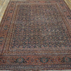 Traditional rug with dense floral navy and rust pattern resting on rustic wooden planks.