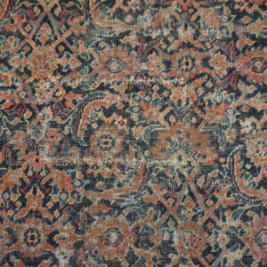 Intricate traditional rug pattern featuring colors of navy, burnt orange, and gray with a worn, low pile.