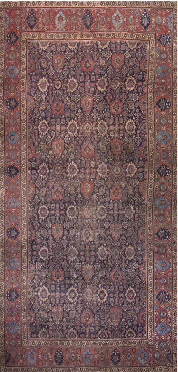 Low-pile rug with a dense navy blue and rust red traditional pattern of repeating floral and medallion motifs.