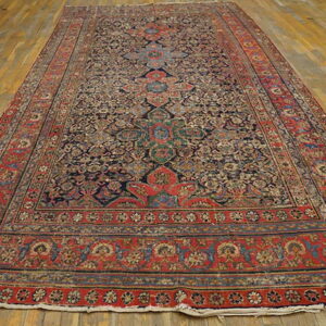 Ornate traditional long runner rug featuring a dark blue field and a wide red border on light hardwood floors.