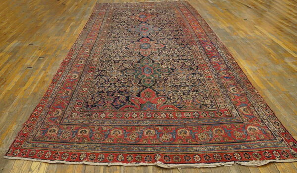 Ornate traditional long runner rug featuring a dark blue field and a wide red border on light hardwood floors.