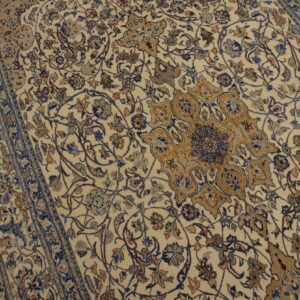 Intricate beige rug featuring a detailed floral pattern and medallion in blue and brown hues on wood floor.