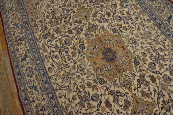 Intricate beige rug featuring a detailed floral pattern and medallion in blue and brown hues on wood floor.