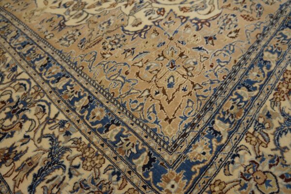 Ornate traditional rug corner displaying blue borders against tan and cream fields with floral motifs.