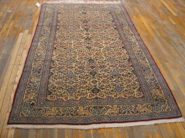 Traditional ivory, blue, and red rug with an all-over floral pattern resting on distressed wood floors.