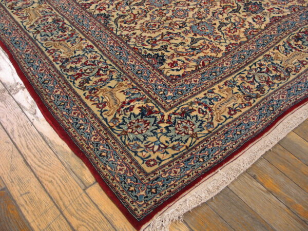 Cream traditional rug with red and blue floral borders rests on light weathered hardwood flooring.