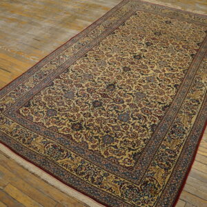 Gold, red, and blue traditional rug with a dense all-over floral pattern on antique wooden floorboards.