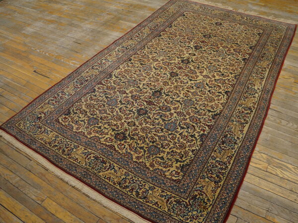 Gold, red, and blue traditional rug with a dense all-over floral pattern on antique wooden floorboards.