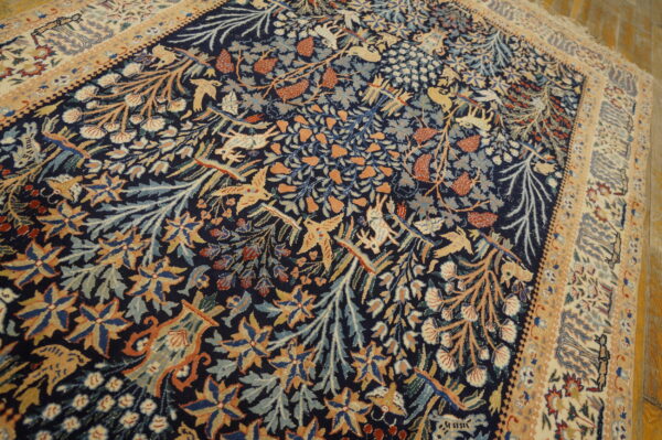 Dark blue rug featuring a dense pattern of orange, gold, and light blue stylized birds, deer, and foliage.