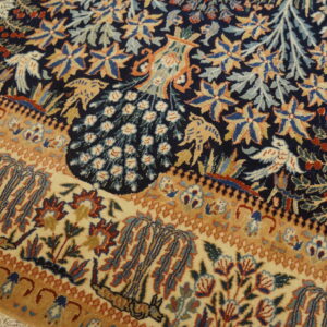 Intricate low-pile rug with navy blue field, tan border, and detailed peacock and bird motifs.
