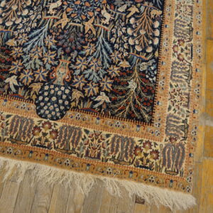 Pictorial rug in navy, beige, and gold with a detailed pattern sits on distressed yellow wood flooring.