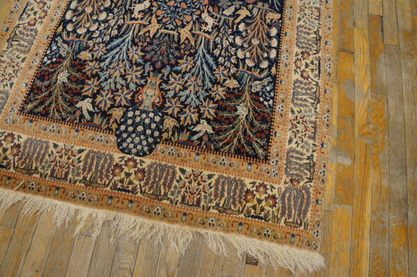 Pictorial rug in navy, beige, and gold with a detailed pattern sits on distressed yellow wood flooring.