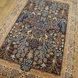 Navy and cream rug with dense floral and stylized animal pattern sits on rustic, yellow-toned wood planks.