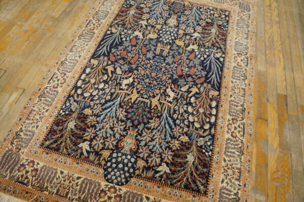 Navy and cream rug with dense floral and stylized animal pattern sits on rustic, yellow-toned wood planks.