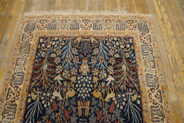 Low pile rug in navy blue and gold with complex botanical and creature patterns on rustic wood planking.