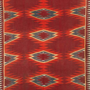 Vertical geometric rug with serrated red diamonds and dark blue centers on a deep red background.