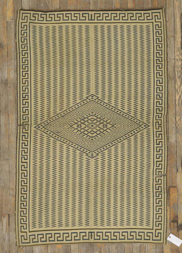 Beige flatweave rug with dark geometric zigzag patterns, a central diamond motif, and meander border.