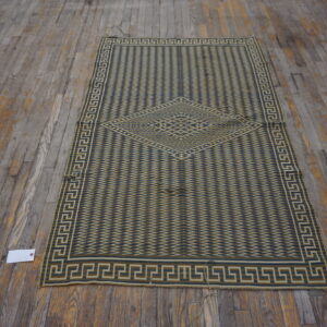 A low-pile green and tan runner with a geometric medallion rests on distressed wide plank flooring.