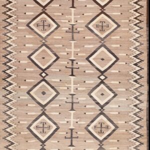 Tan flatweave rug displaying dark and light geometric diamonds and zig-zag border motifs on a neutral tan background.