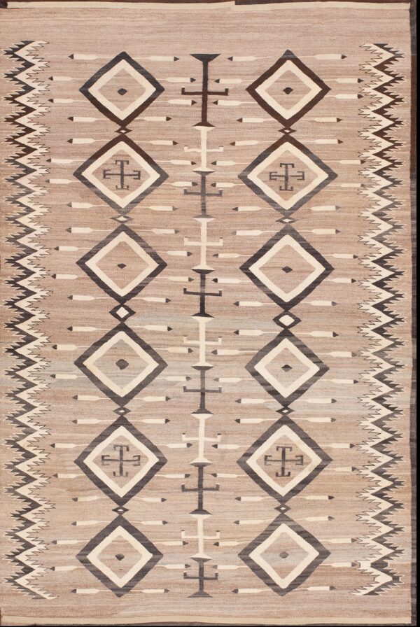 Tan flatweave rug displaying dark and light geometric diamonds and zig-zag border motifs on a neutral tan background.