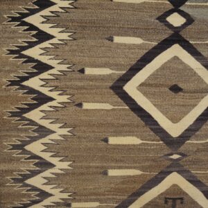Brown, cream, and dark geometric flatweave rug featuring diamond and zigzag motifs on a wood floor.