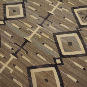 Geometric low-pile rug with concentric diamond motifs and cross shapes against a striated brown and gray background.