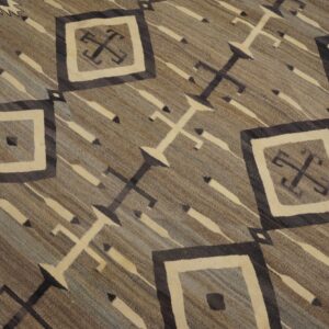 Low-pile geometric rug featuring diamonds, crosses, and diagonal stripes in gray, brown, and cream tones.