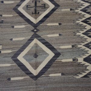 Gray and taupe flat-weave rug with geometric diamonds, cross motifs, and zigzag borders in charcoal and cream.