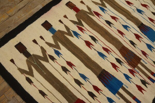 Cream rug with brown stylized figures and rows of red and blue arrow motifs on plank flooring.