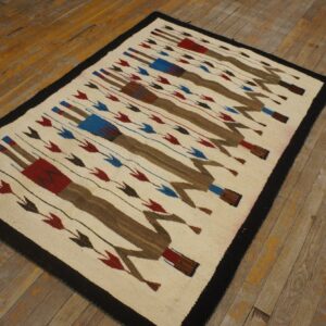 Low-pile cream rug featuring brown, red, and blue repeating figures on worn wooden flooring.