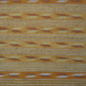 Low-pile rug in gold and brown stripes with geometric arrow motifs over diagonal wood flooring.