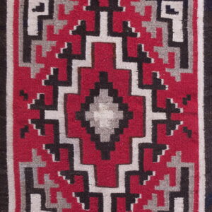 Flat-weave rug with a central diamond motif surrounded by red, black, and gray geometric borders.
