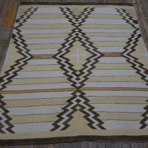 Cream and tan striped flatweave rug features dark brown zigzag columns forming central diamonds on wooden floors.