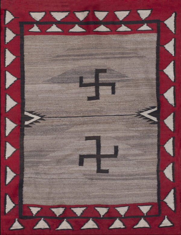 Gray flat-woven rug with a red triangular border surrounding two black angular symbols.