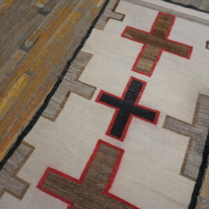 Cream, brown, and red cross patterns line this low-pile runner on a rustic wood floor.