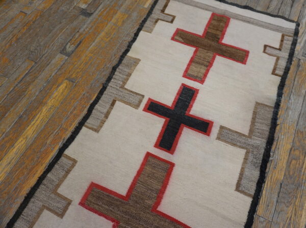 Cream, brown, and red cross patterns line this low-pile runner on a rustic wood floor.